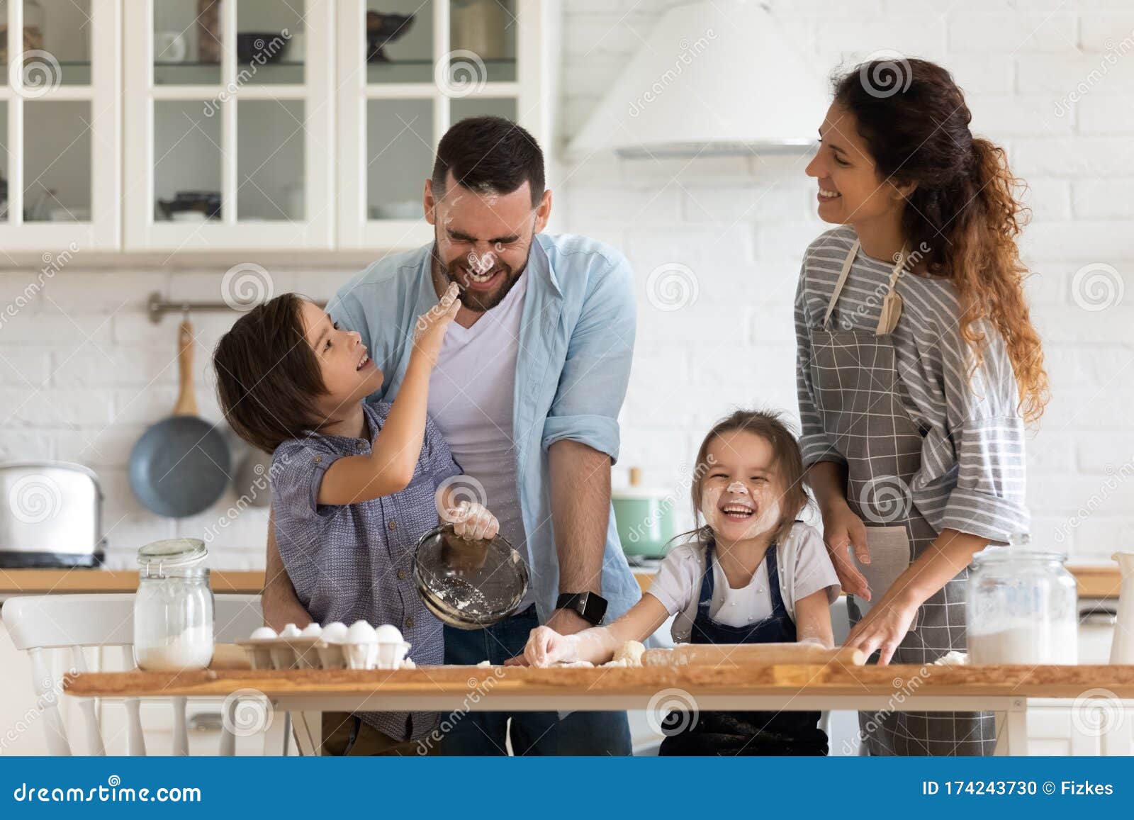 overjoyed parents with little kids have fun cooking in kitchen