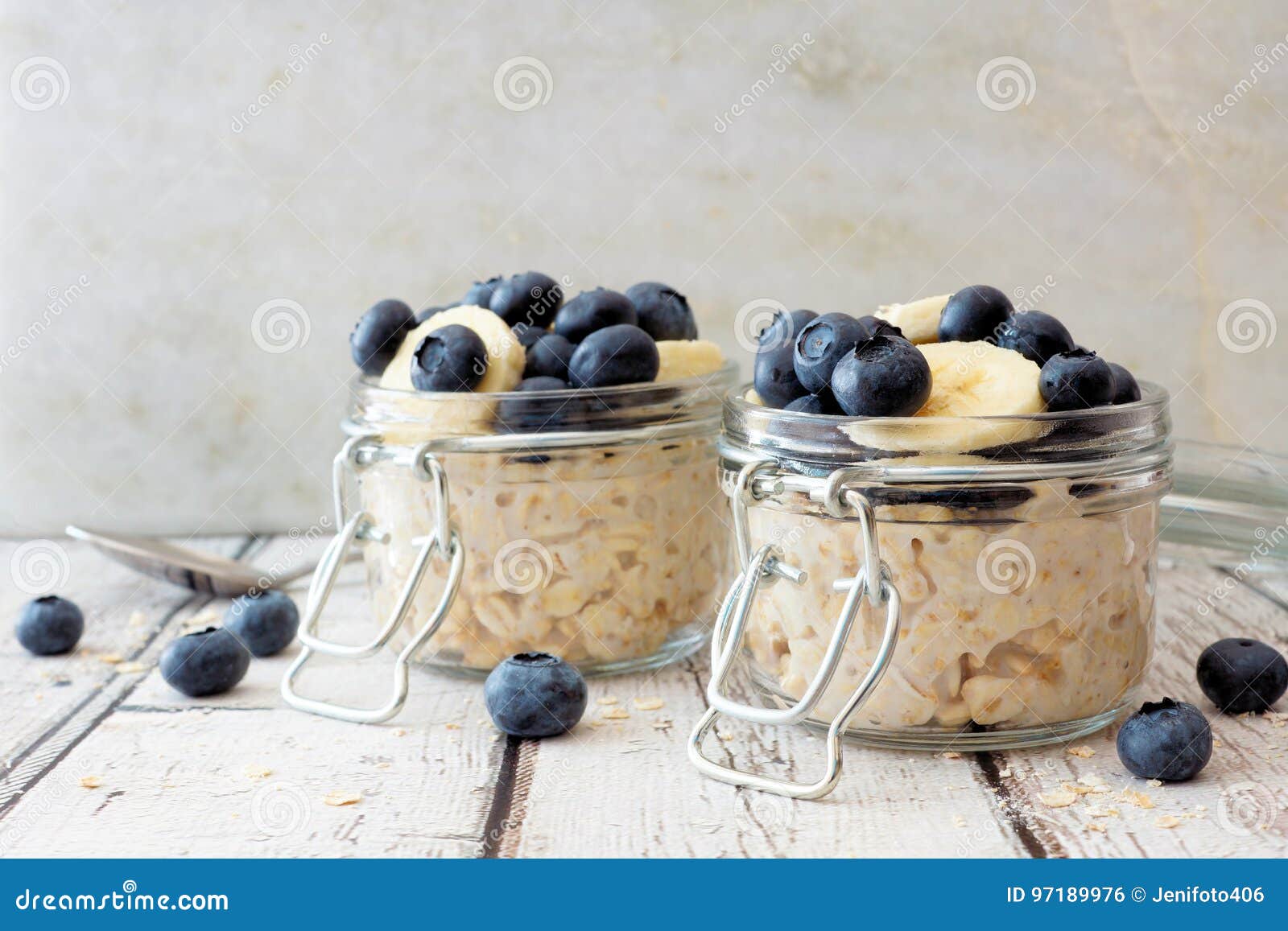 overnight oats with blueberries and bananas on a white wood background