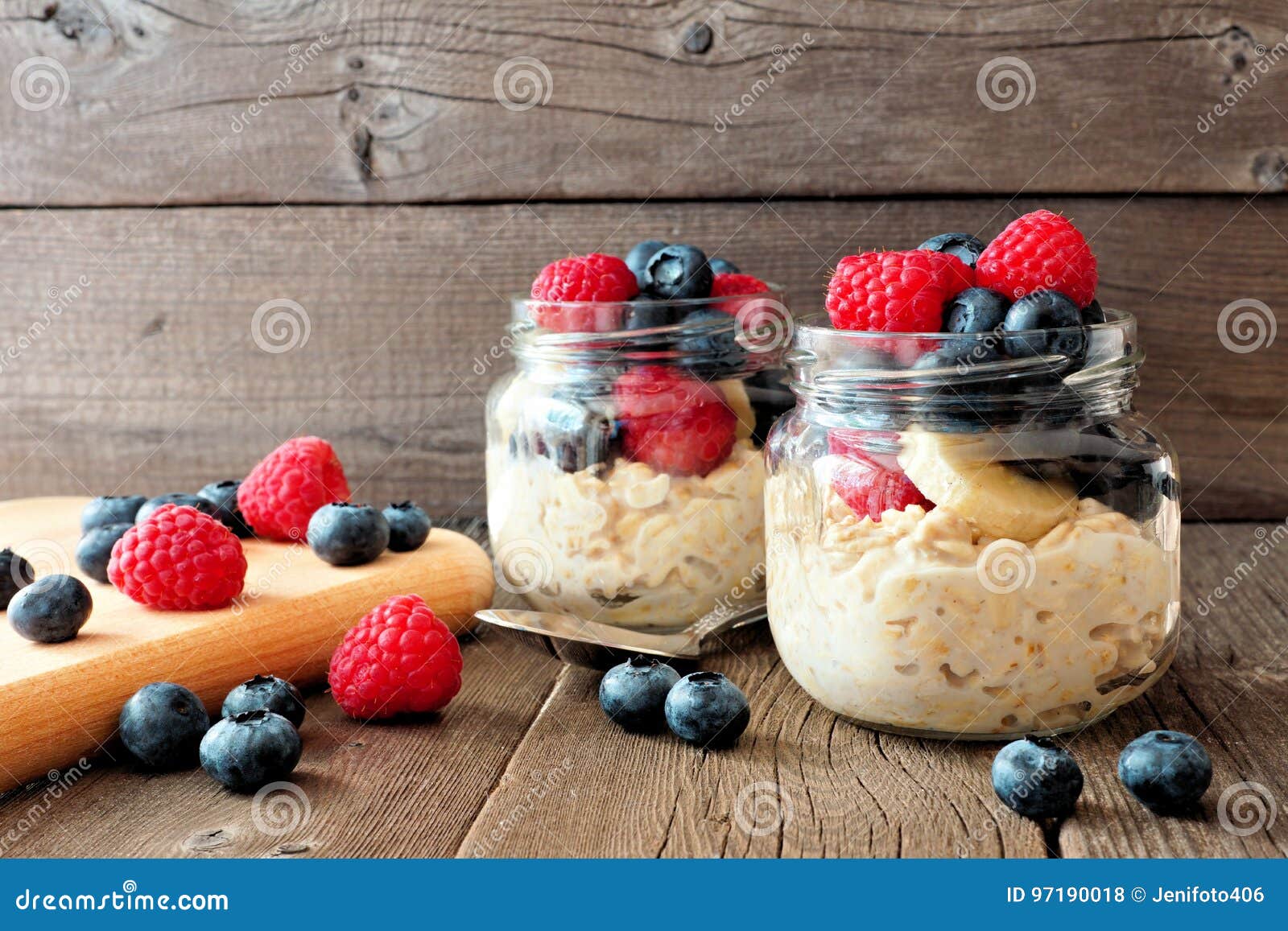 overnight oats with blueberries and raspberries in jars on rustic wood