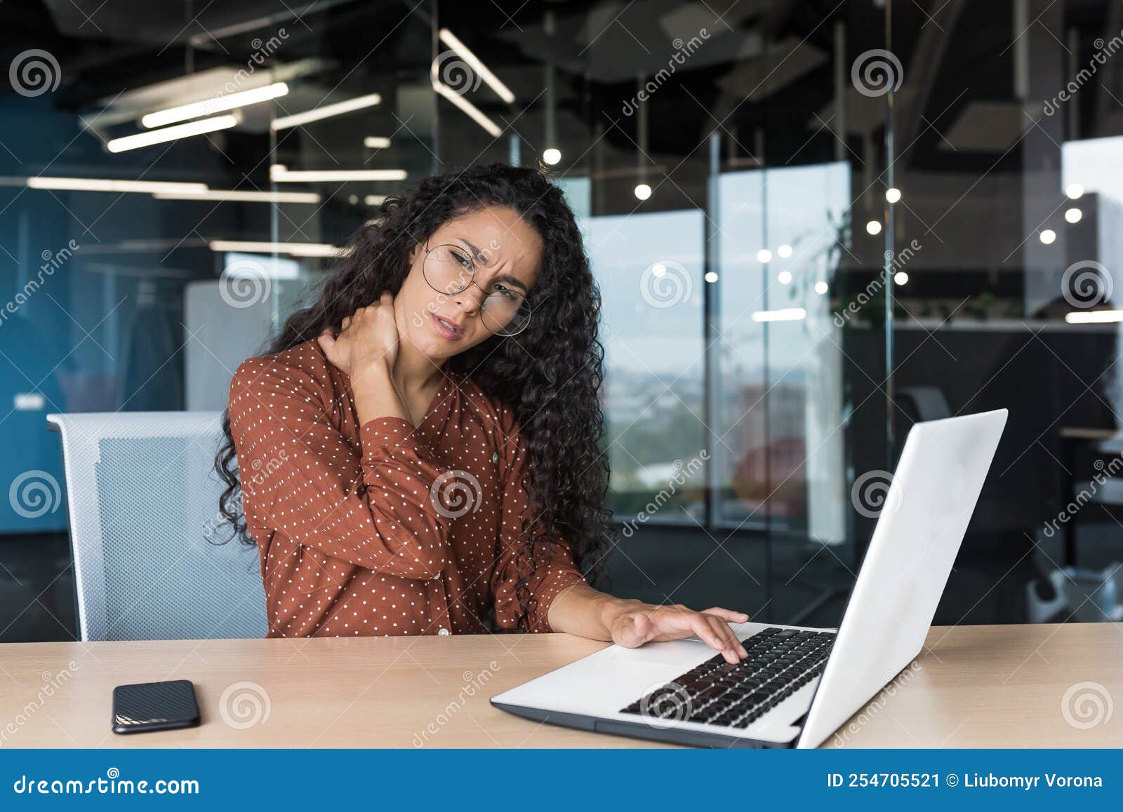 overtired hispanic woman working in modern office using laptop, businesswoman inside