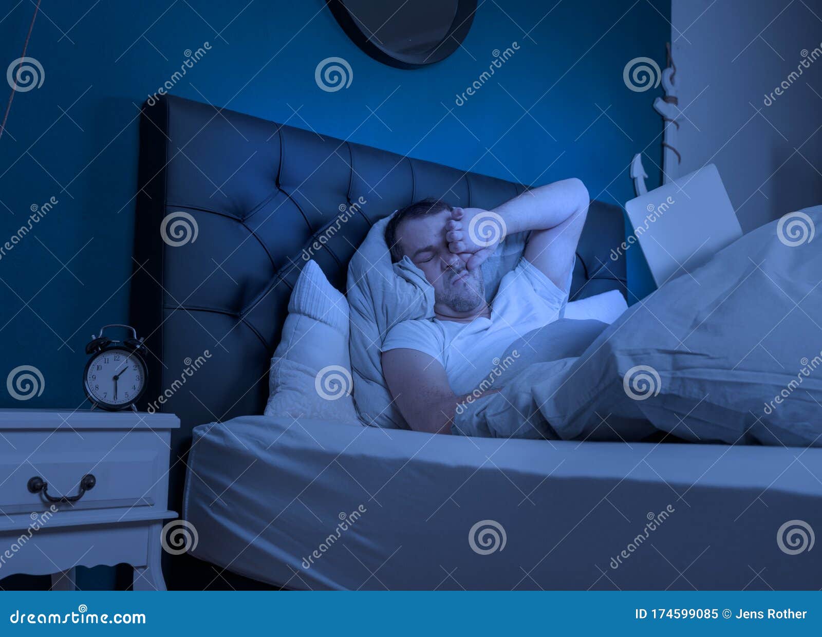 an overtired man works at night on his laptop