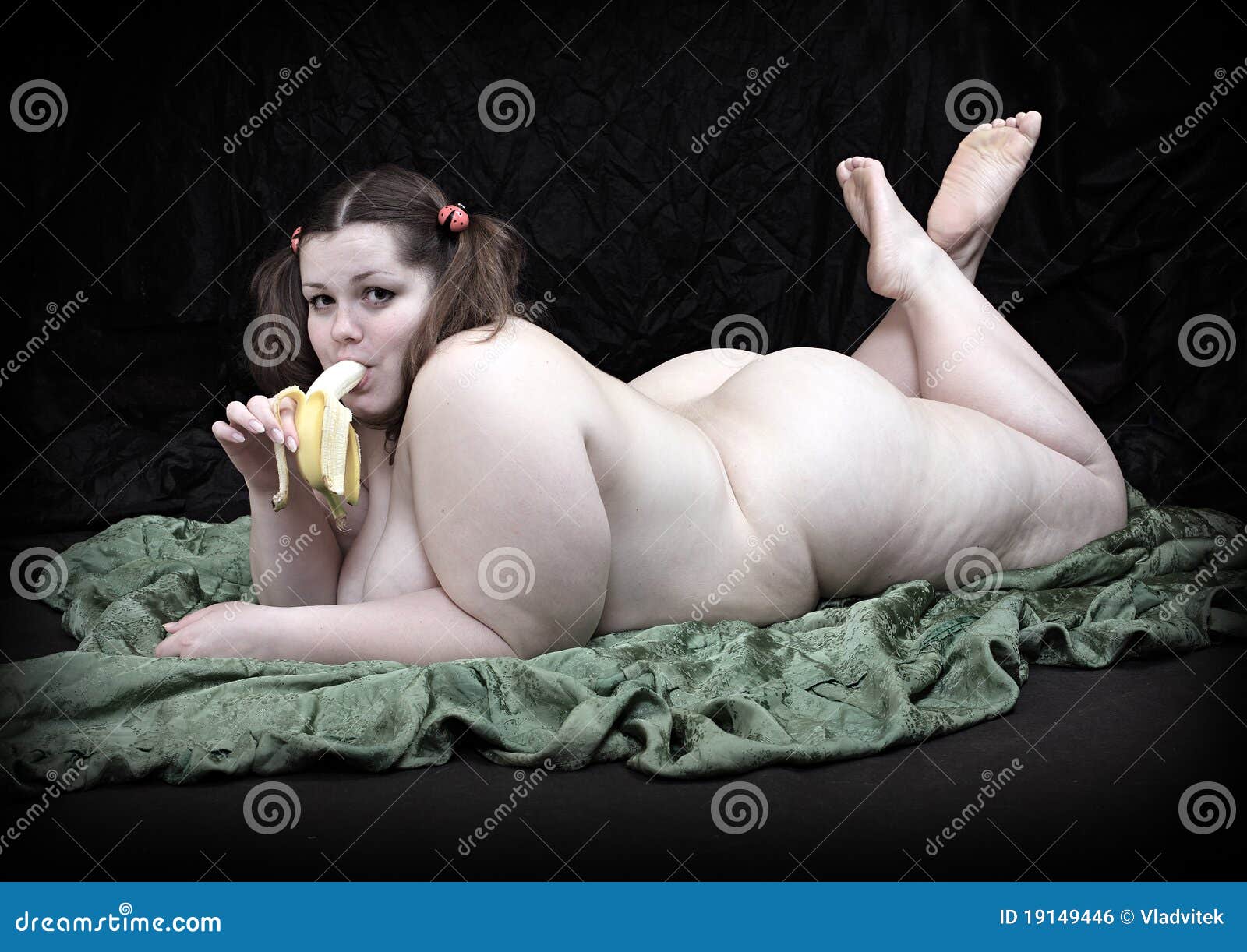 Naked overweight woman eating fresh ripe bananas on black background. 