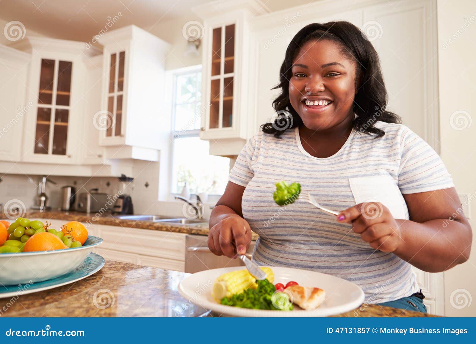 overweight woman eating healthy meal in kitchen