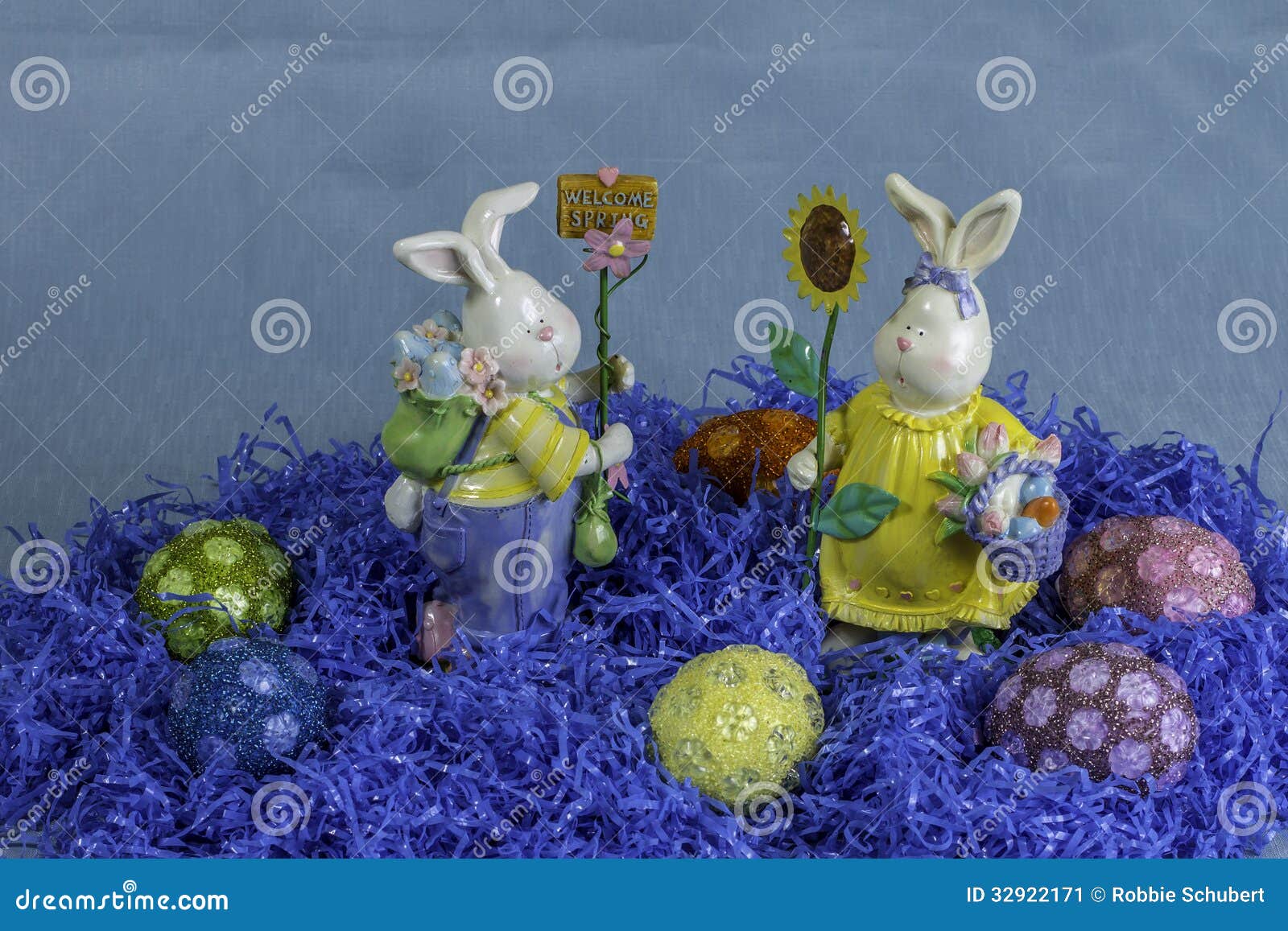 Ovos da páscoa 4. Um grupo de ovos da páscoa cercados pela grama azul falsificada e pelas duas estátuas do coelho.