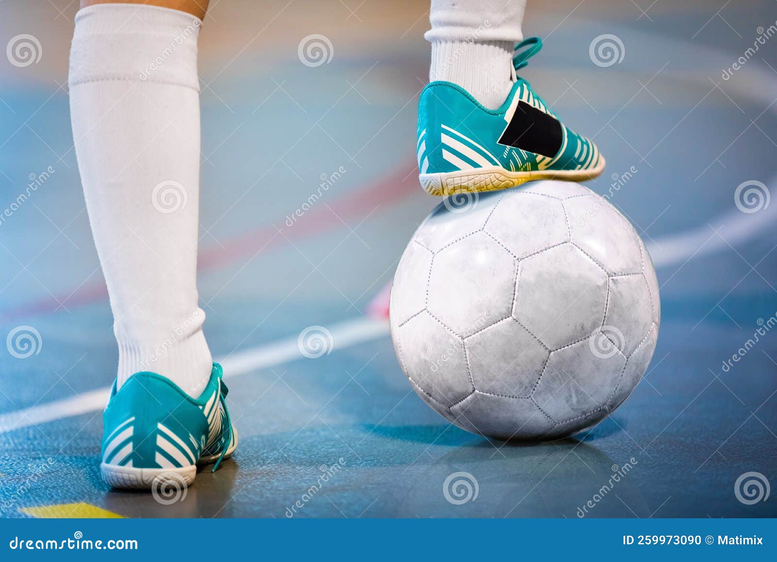 Menino jogador de futebol está pisando na bola na sala