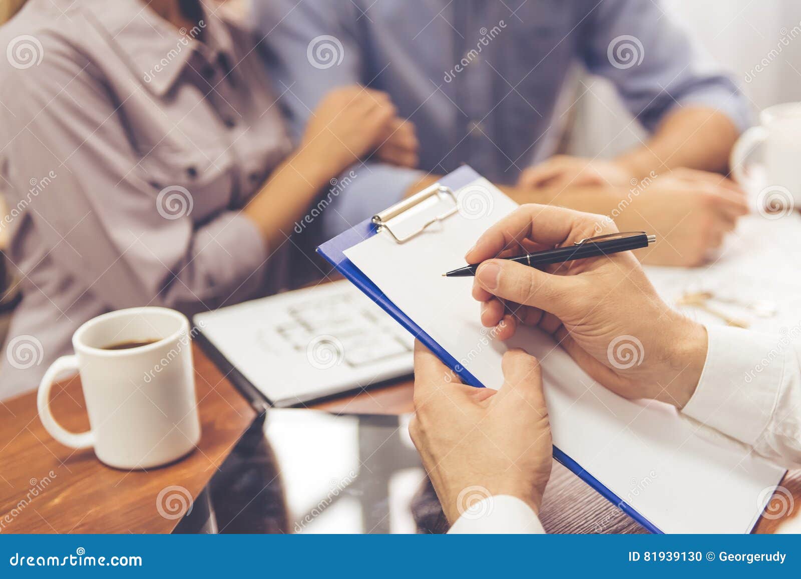 Paar en een makelaar in onroerend goed. Bebouwd beeld van mooi paar die aan makelaar in onroerend goed spreken, die nota's maakt