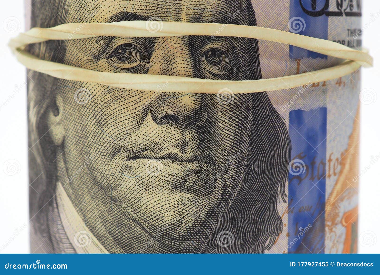 a pack of dollars is rolled up, pulled together with an elastic band. 100 dollar bill in color, a new sample. franklin`s face is