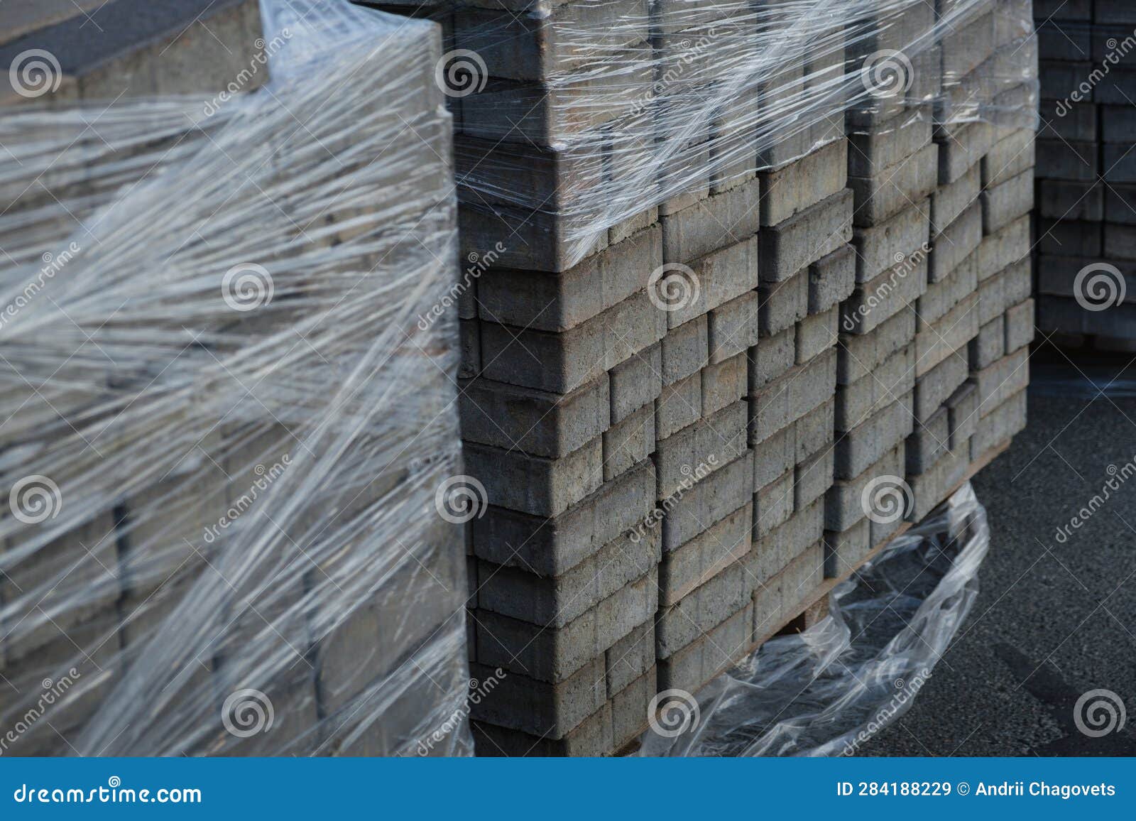 Packs of Gray Cement Paving Slabs are Wrapped in Plastic Wrap in the
