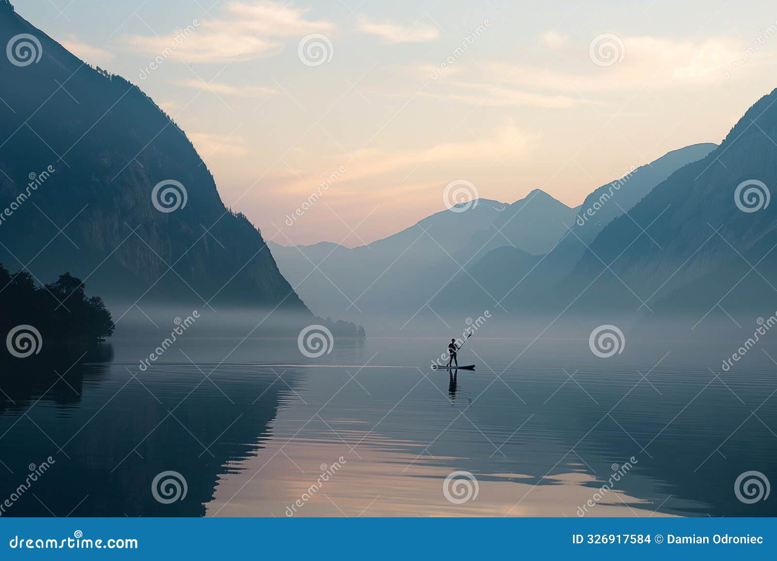 paddleboarder gliding across a serene lake at dawn