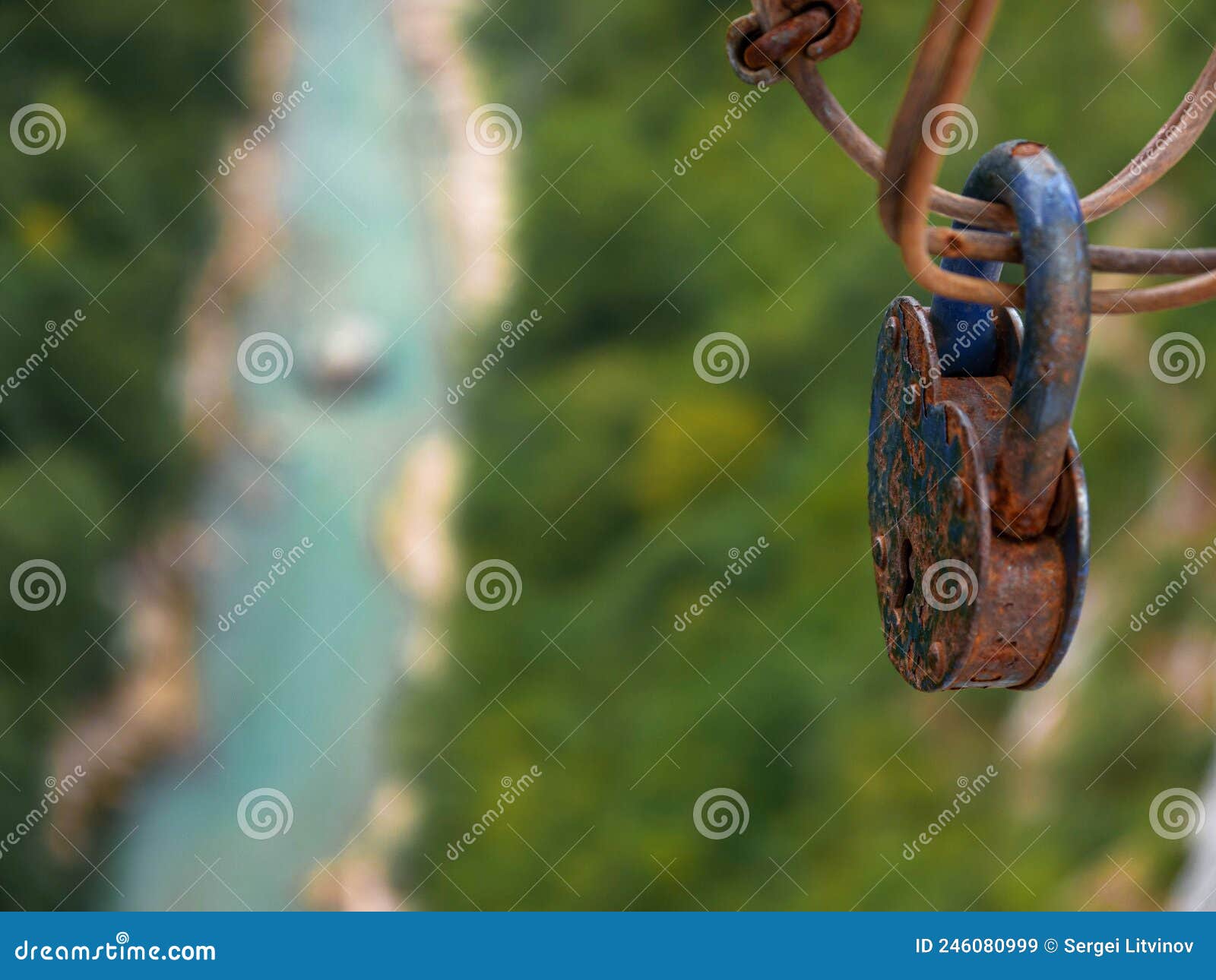 a large padlock hanging on a bridge over a green gorge with a river