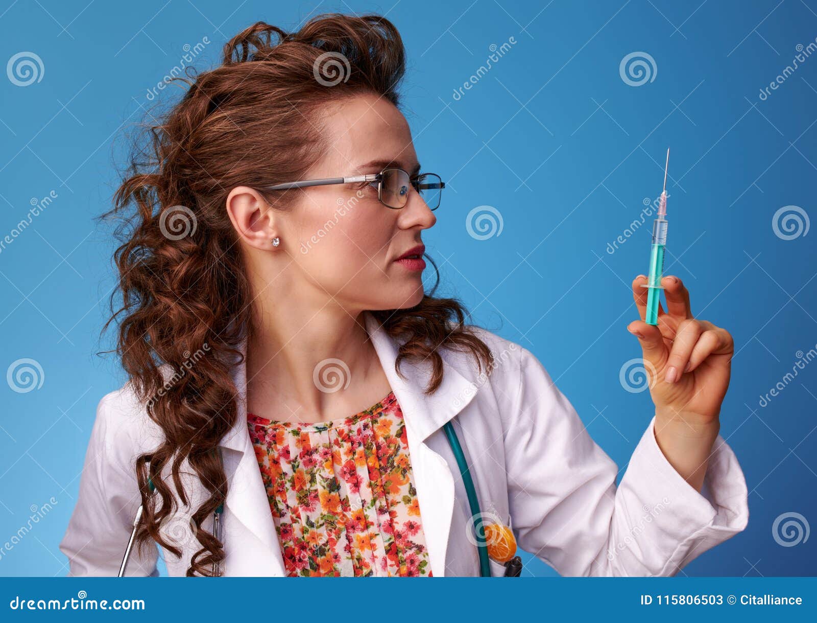 paediatrician woman looking at syringe on blue