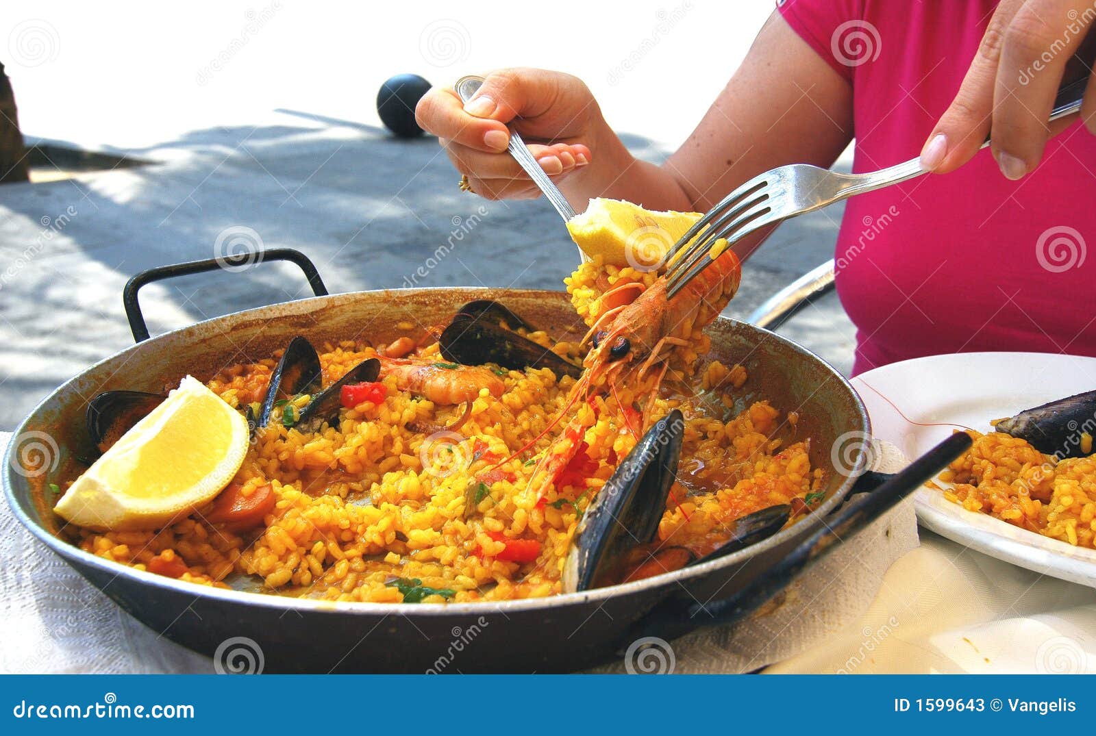 Le femme prenant une aide de la Paella avec la crevette et des moules de elle fait cuire le carter.