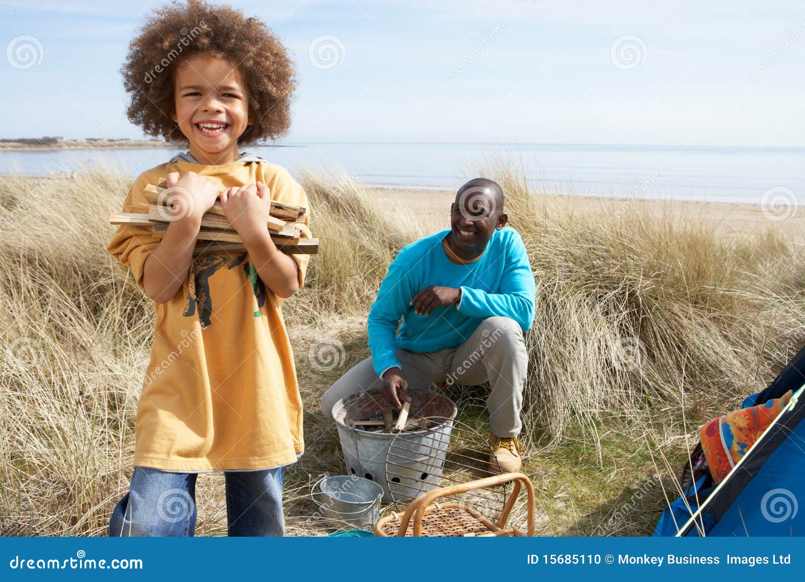 Pai e filho que coletam a lenha na praia. Pai e filho que coletam a lenha no feriado de acampamento da praia