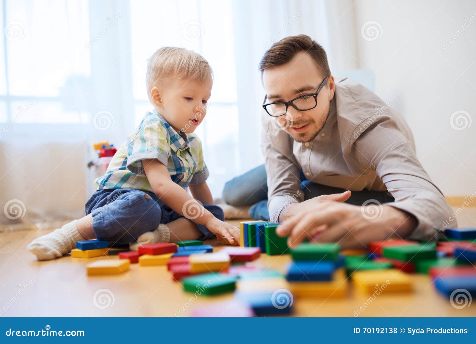 Pai e filho que jogam com blocos do brinquedo em casa. Família, infância, faculdade criadora, atividade e conceito dos povos - pai feliz e filho pequeno que jogam com blocos do brinquedo em casa