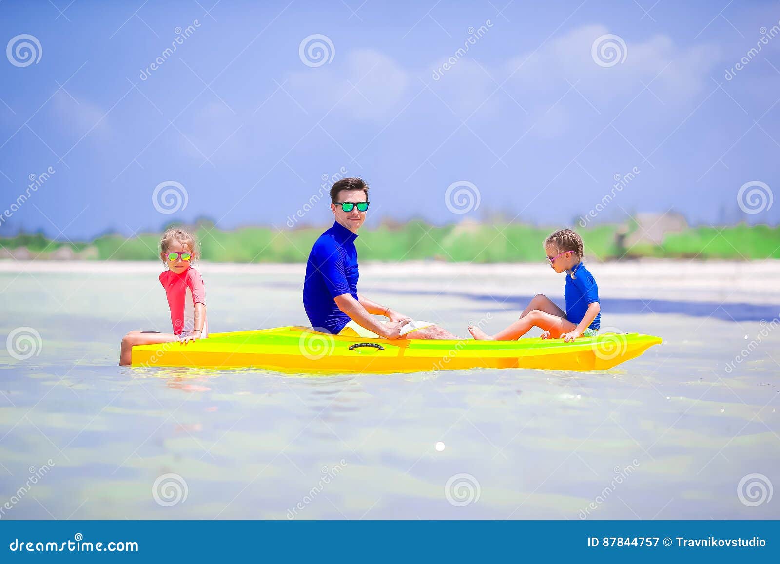 Pai novo e duas crianças que kayaking no mar. Pai novo e dois suas filhas pequenas que kayaking no mar morno tropical