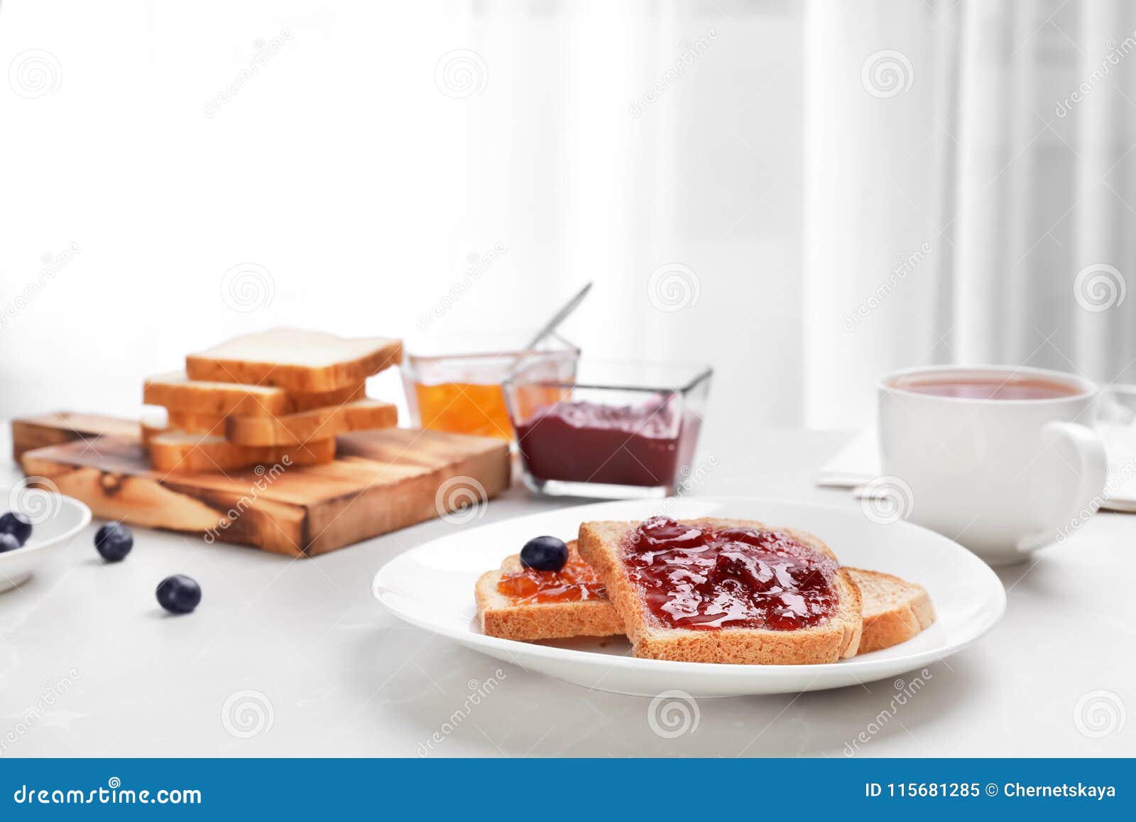 Pains grillés avec la confiture et la tasse de thé sur la table