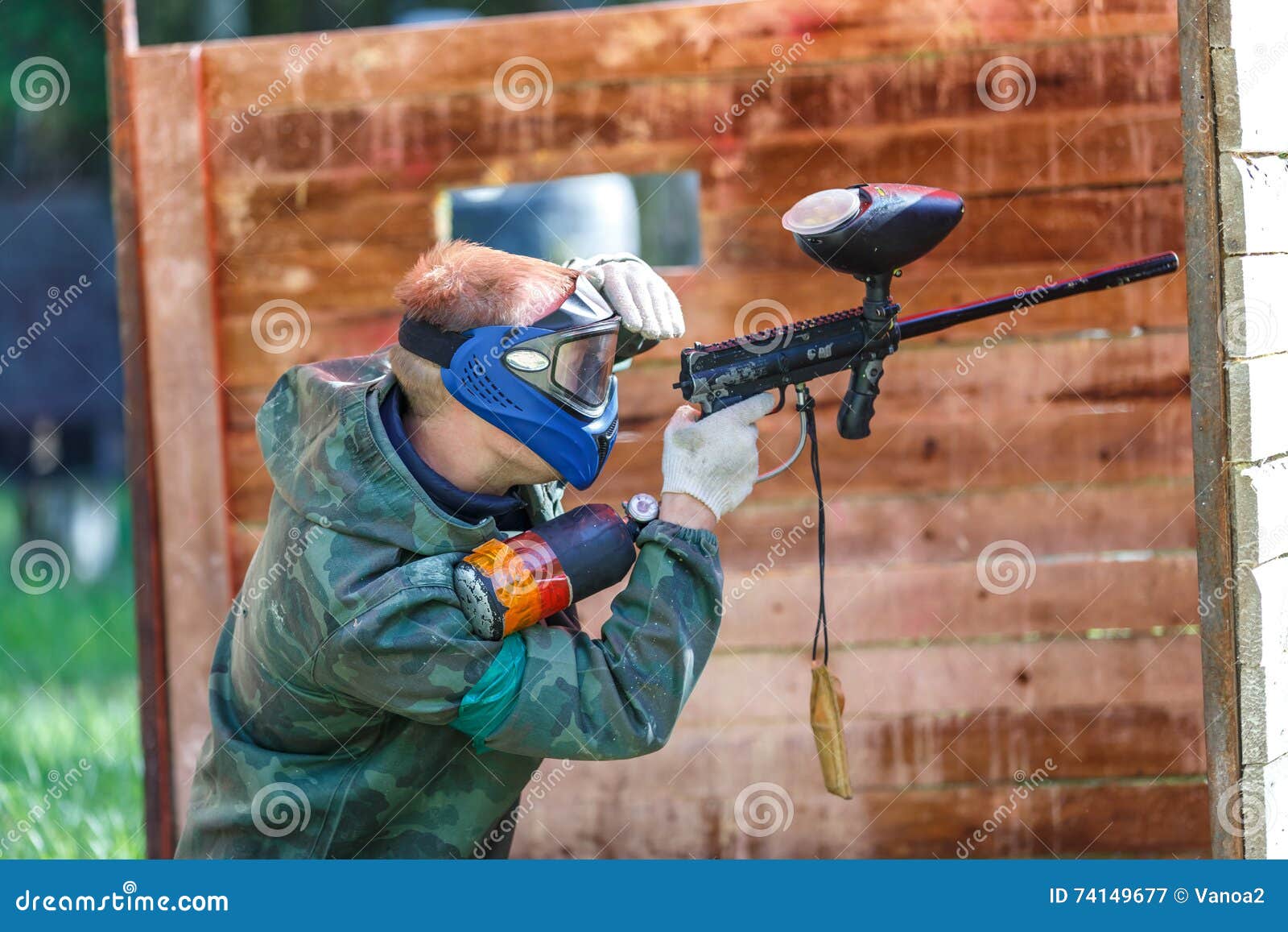 Paintball Player in Blue Helmet Shooting from Paint Gun Stock Image