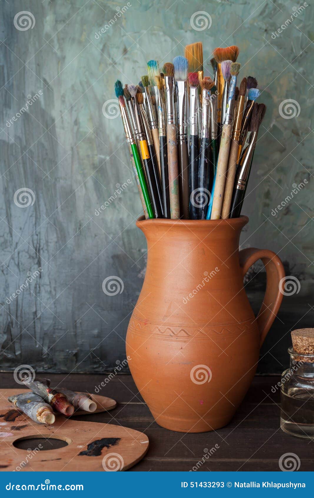 paintbrushes in a jug from potters clay, palette and paint tubes