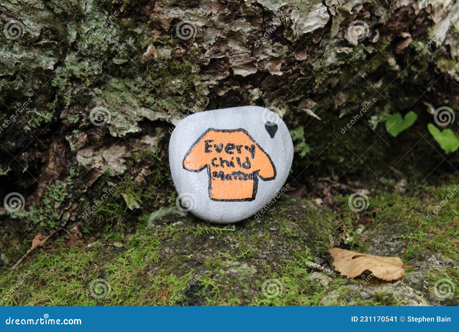 a painted rock at the base of a tree along a trail in nova scotia orange shirt every child matters