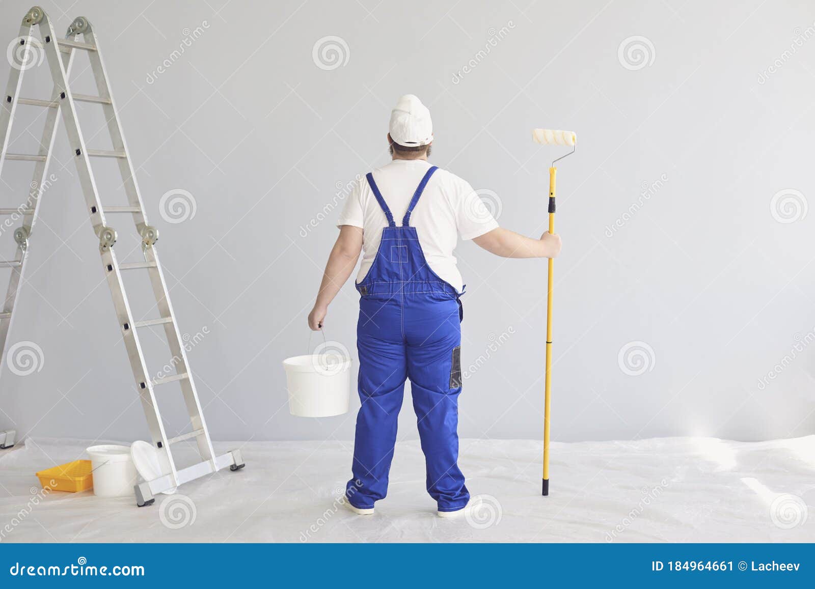 Painter Painting. Funny Male Painter with a Roller Skater Standing Paints  in the Background. Stock Image - Image of interior, humor: 184964661