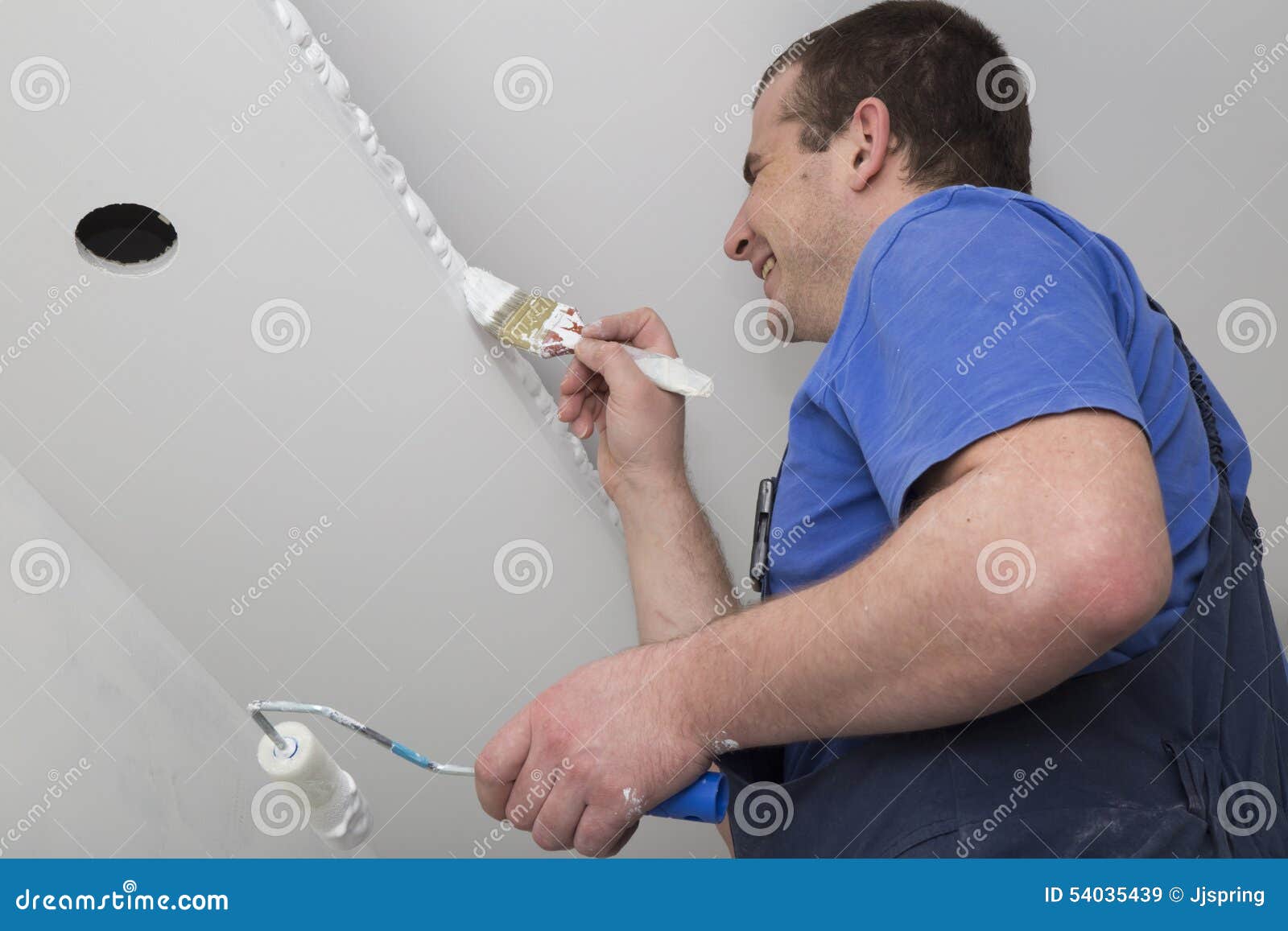 Painter Painting a House Ceiling with Brush and Roller Stock Image