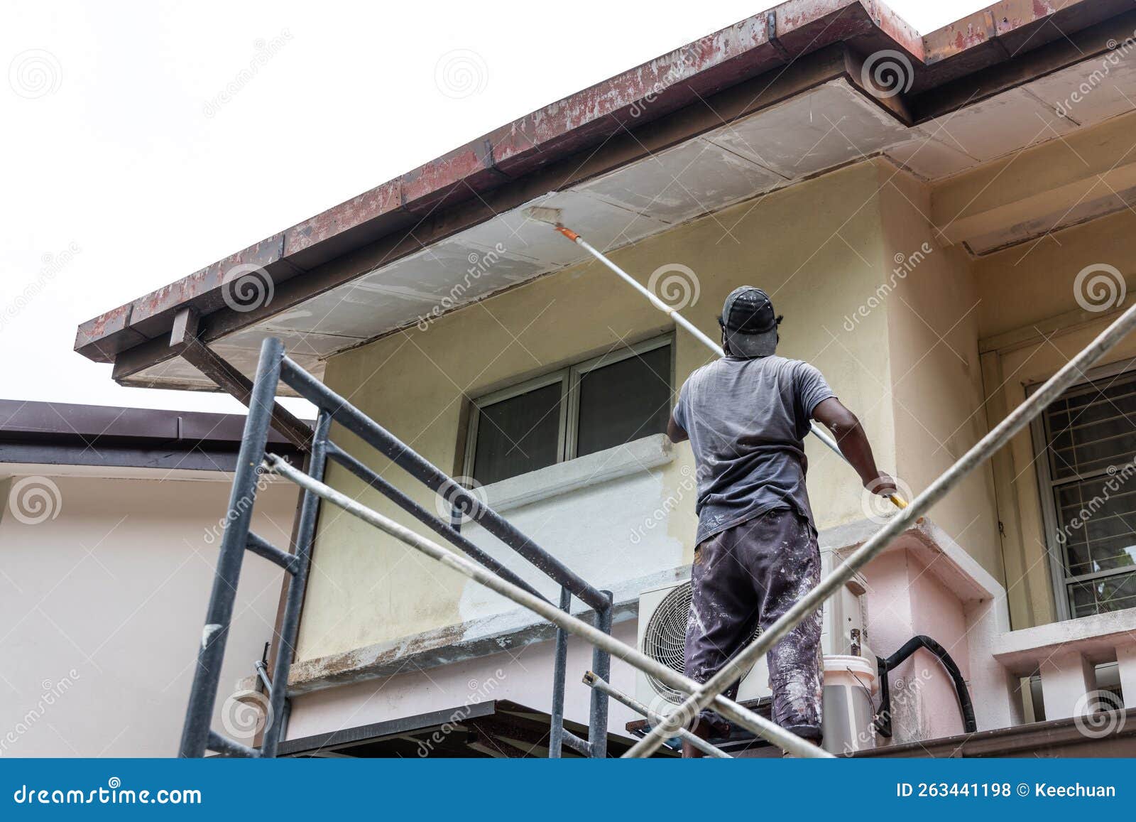 painter worker adding undercoat foundation paint onto ceiling with roller at residential building