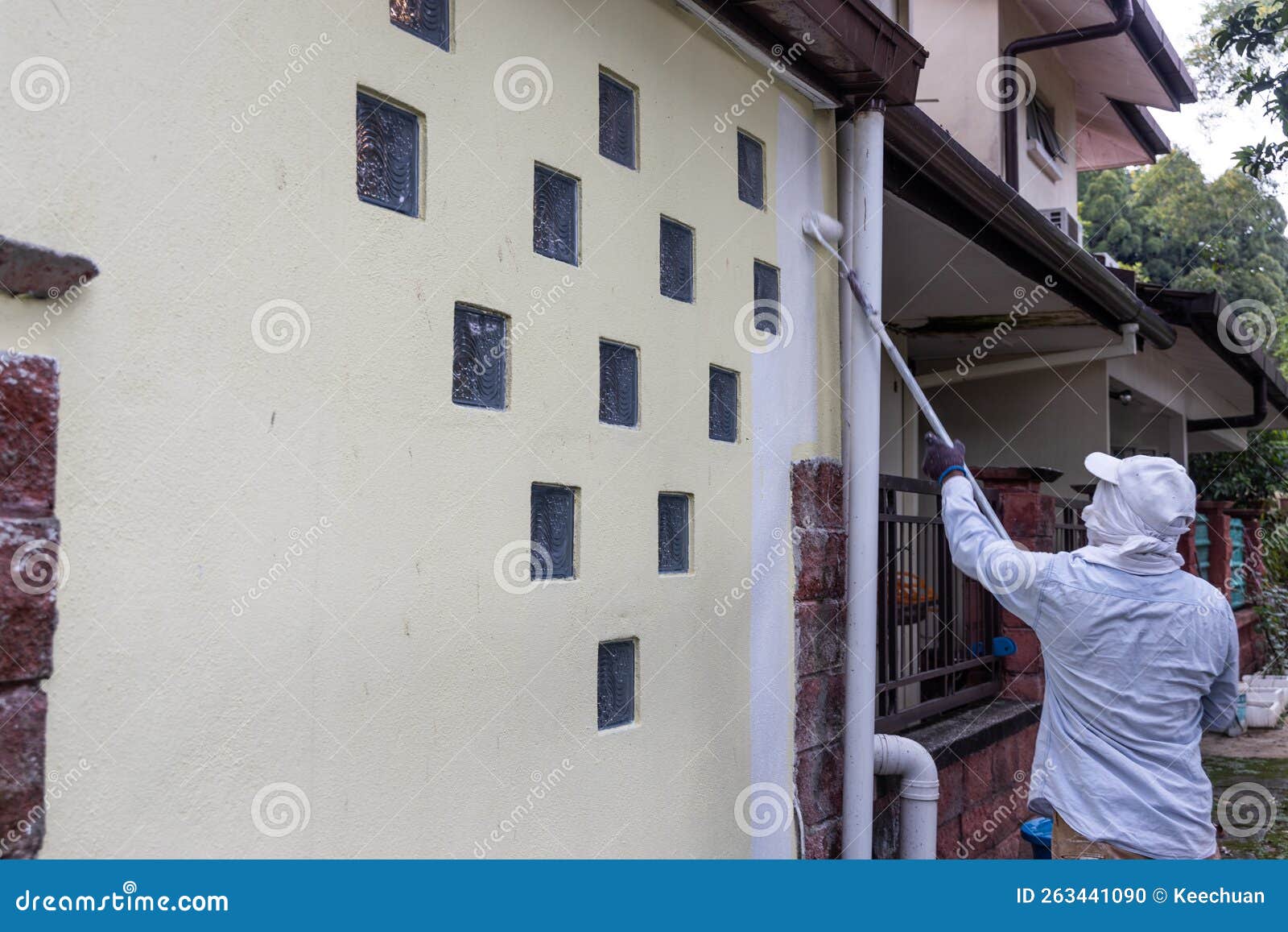 Painter Worker Adding Undercoat Foundation Paint Onto Wall with Roller