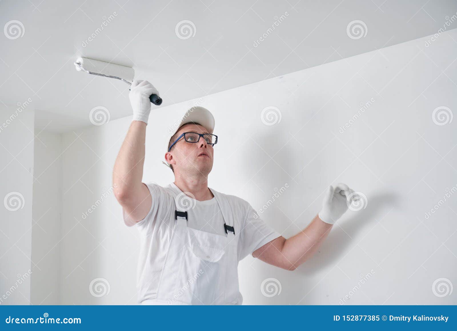 Painter Worker With Roller Painting Ceiling Surface Into