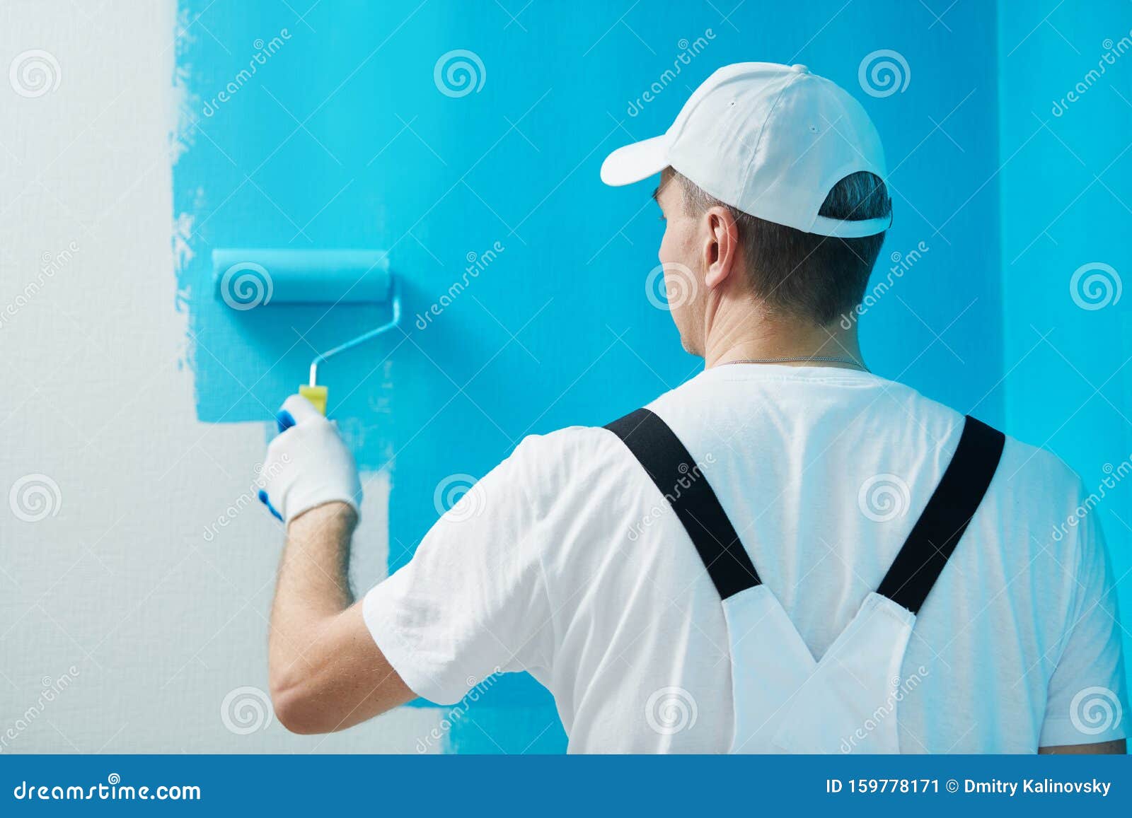 painter worker with roller painting wall surface into color