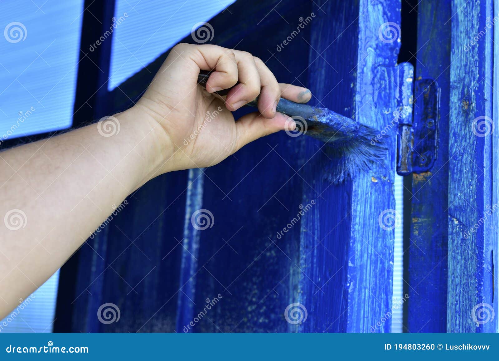 Painting the Door with Blue Paint Brush in Hand Stock Photo Image of blue, orange 194803260