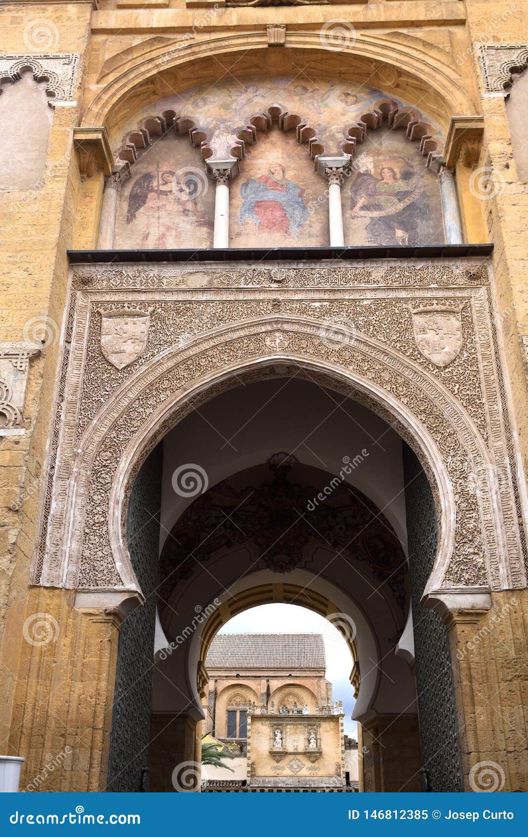 painting the facade of the door of the el perdon, moorish facade of the great mosque in cordoba, andalusia, spain