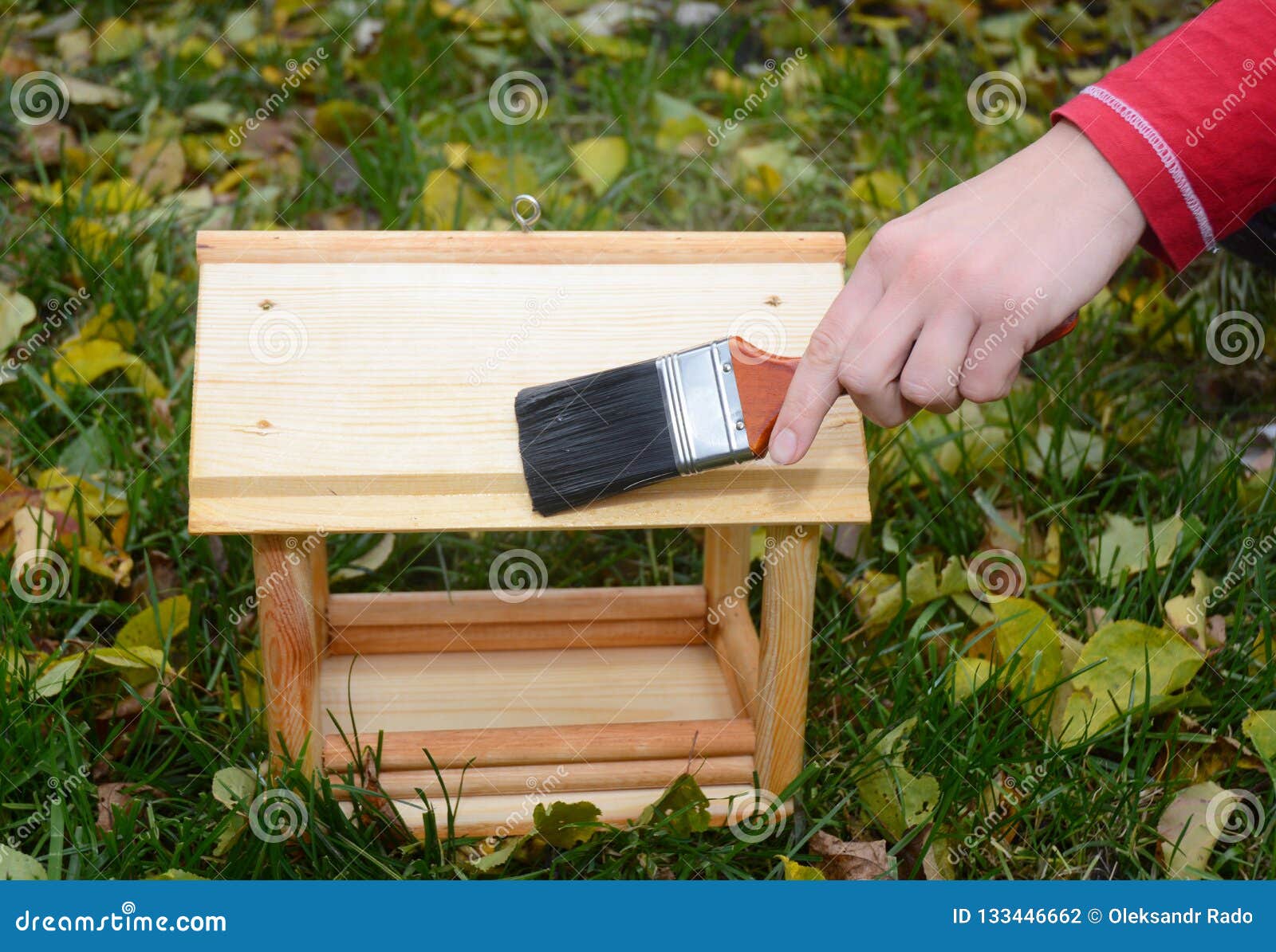 Painting Wooden Bird Feeder With Drying Oil For Rain Protection. Stock Photo Image of