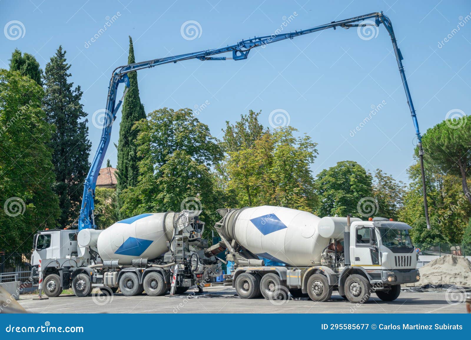 Pair of Cement Trucks with Extended Hydraulic Systems Pouring Cement