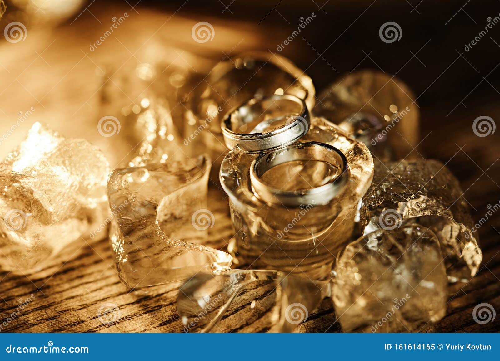 Pair of Gold Wedding Rings on Ice Cubes Sparkle and Reflection Stock