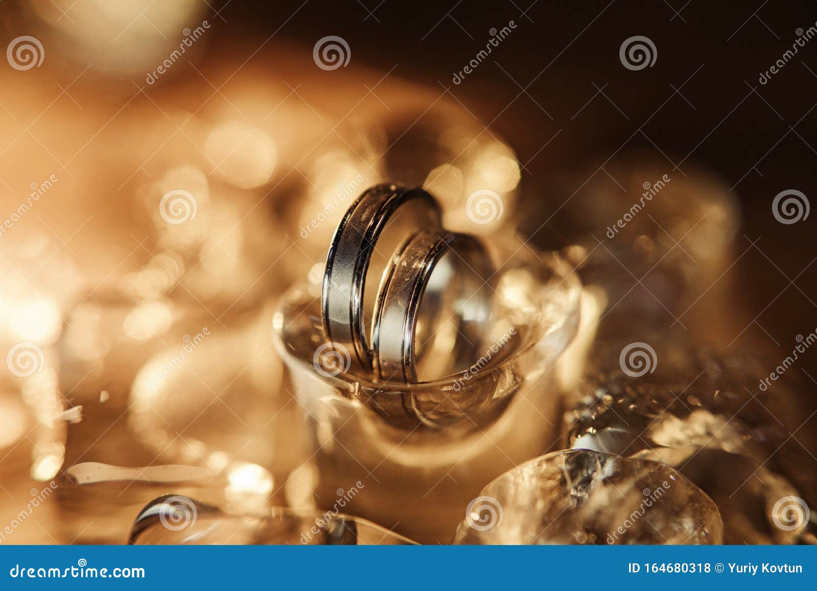 Pair of Gold Wedding Rings on Ice Cubes Sparkle and Reflection Stock