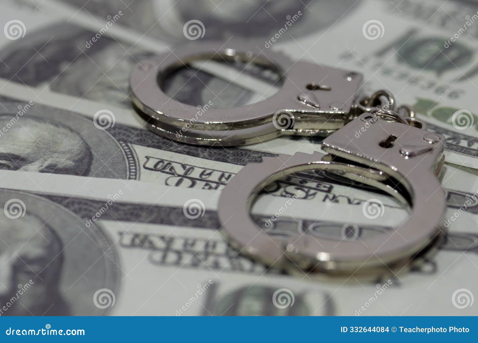 a pair of handcuffs lying on a bed of u.s. dollar bills. this juxtaposition suggests the corrupting influence of money or the