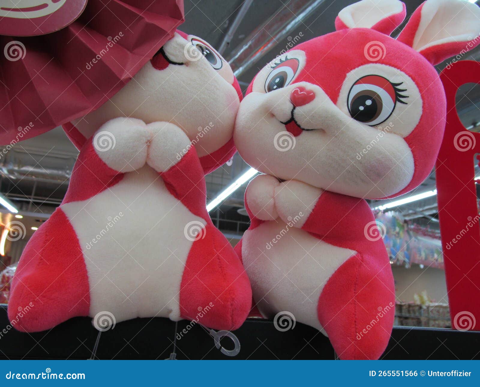 a pair of identical similar same red white rabbit soft toy plushies on display
