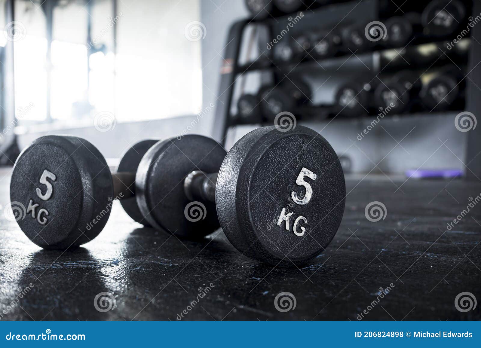 A Pair of 5 Kilogram Dumbbells Lying on the Floor of a Gym, with a
