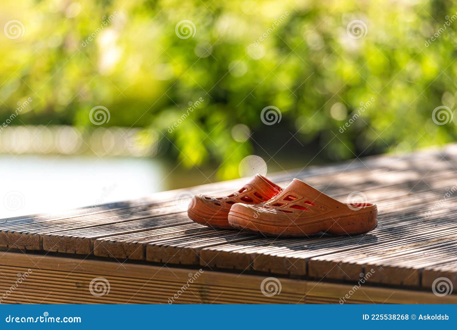 A Pair of Orange Rubber Clogs on the Pier by the Lake, Closeup Stock