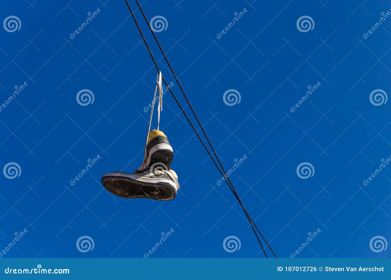 Sneakers on wires. Vector illustration with silhouette of lone shoes  hanging on power line. Blue pastel background Stock Vector | Adobe Stock