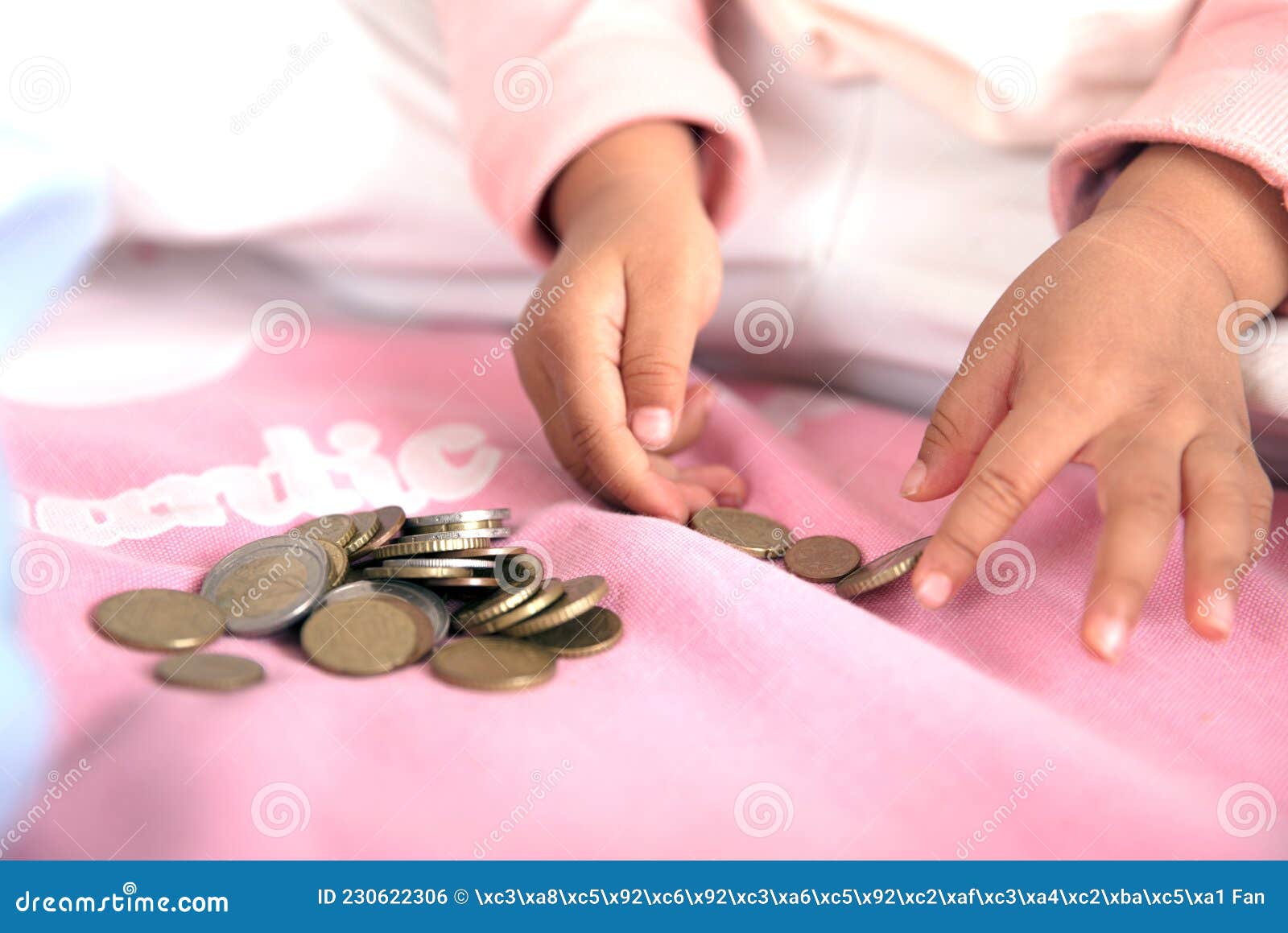 a pair of small hands are playing with euro coins