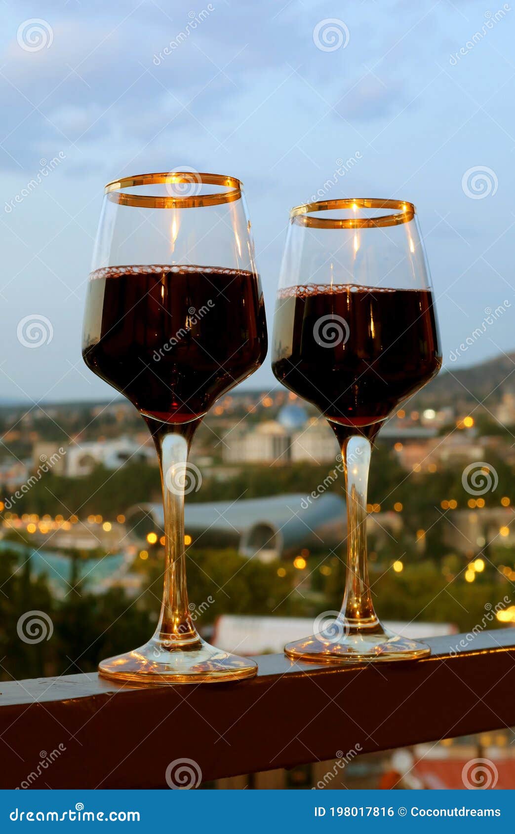 Pair of Wine Glasses on the Balcony with Blurry City Evening View in
