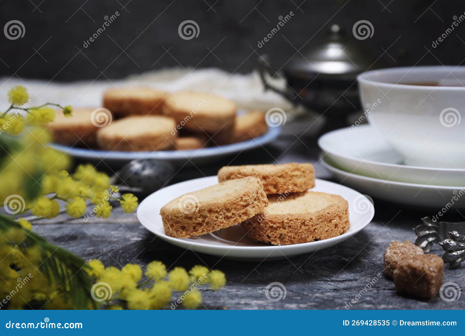 palets bretons, french cookies. shortbread breton cookies, cup of tea and bouquet of mimosa