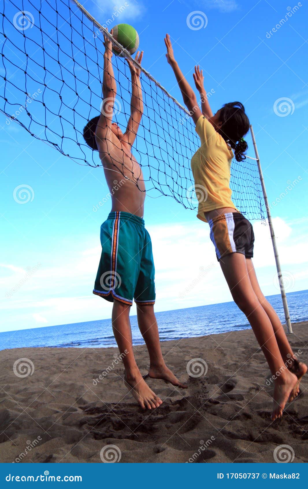 Adolescenti asiatici che giocano pallavolo della spiaggia