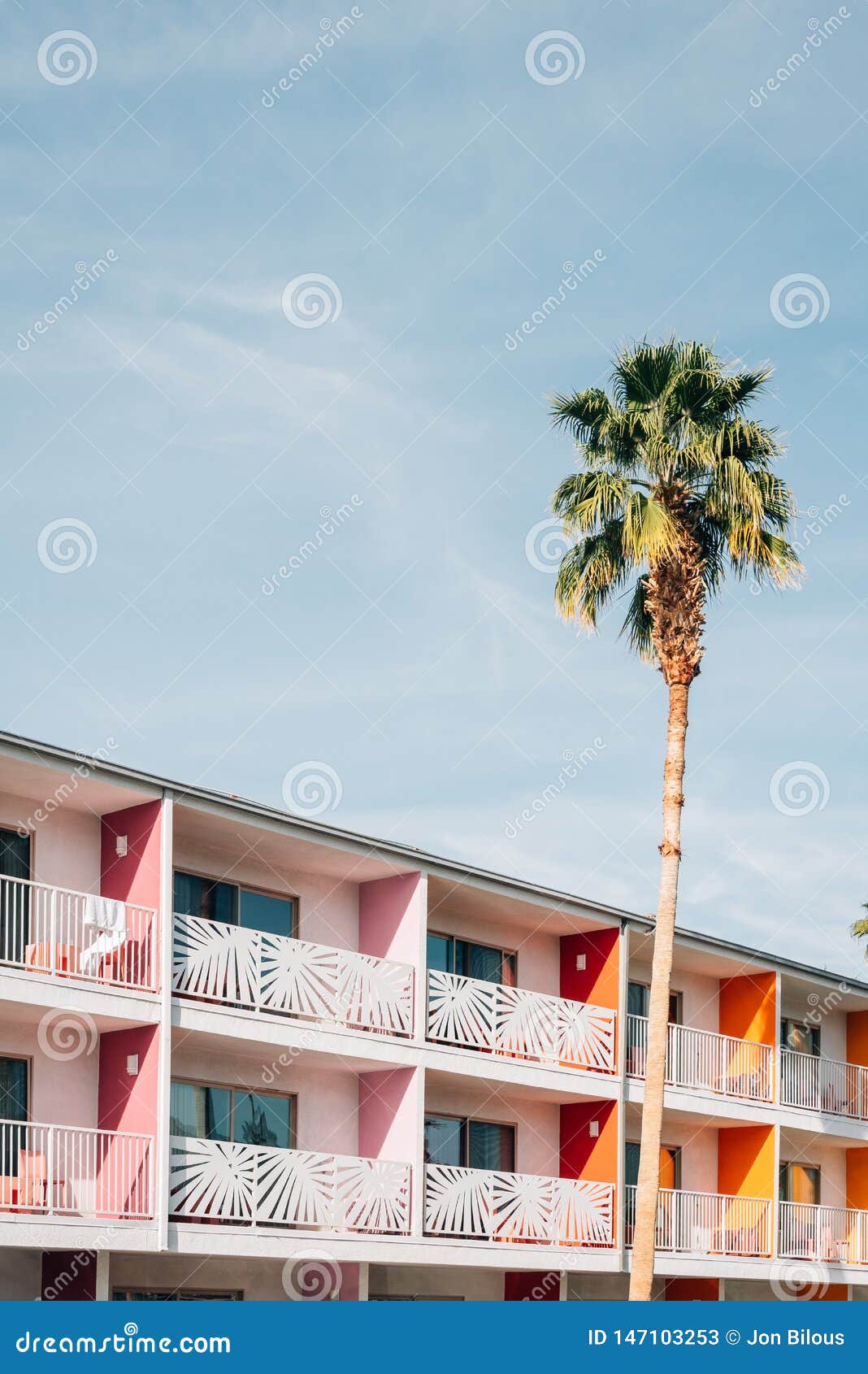 palm tree and colorful hotel with balconies in palm springs, california