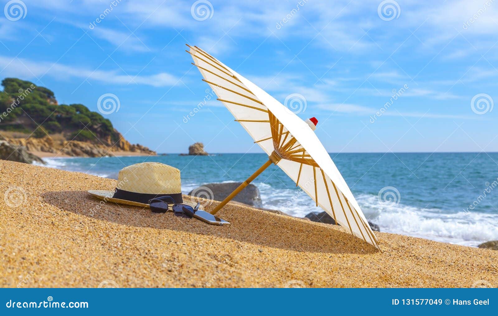 panama hat and beach umbrella on the sandy beach near the sea. summer holiday and vacation concept for tourism