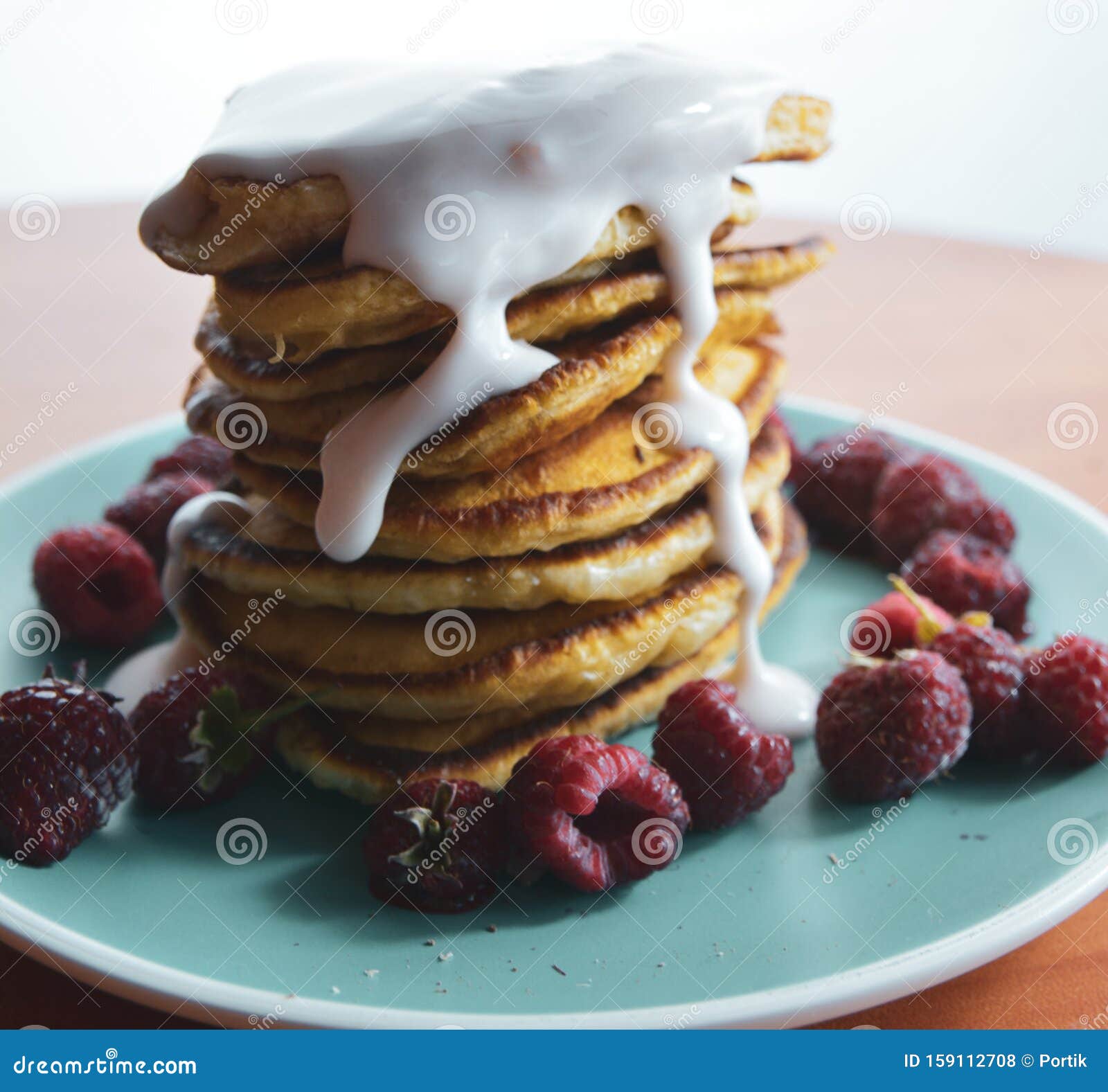 Pancake Con Yogurt Fluente Su Una Piastra Blu Con Lamponi