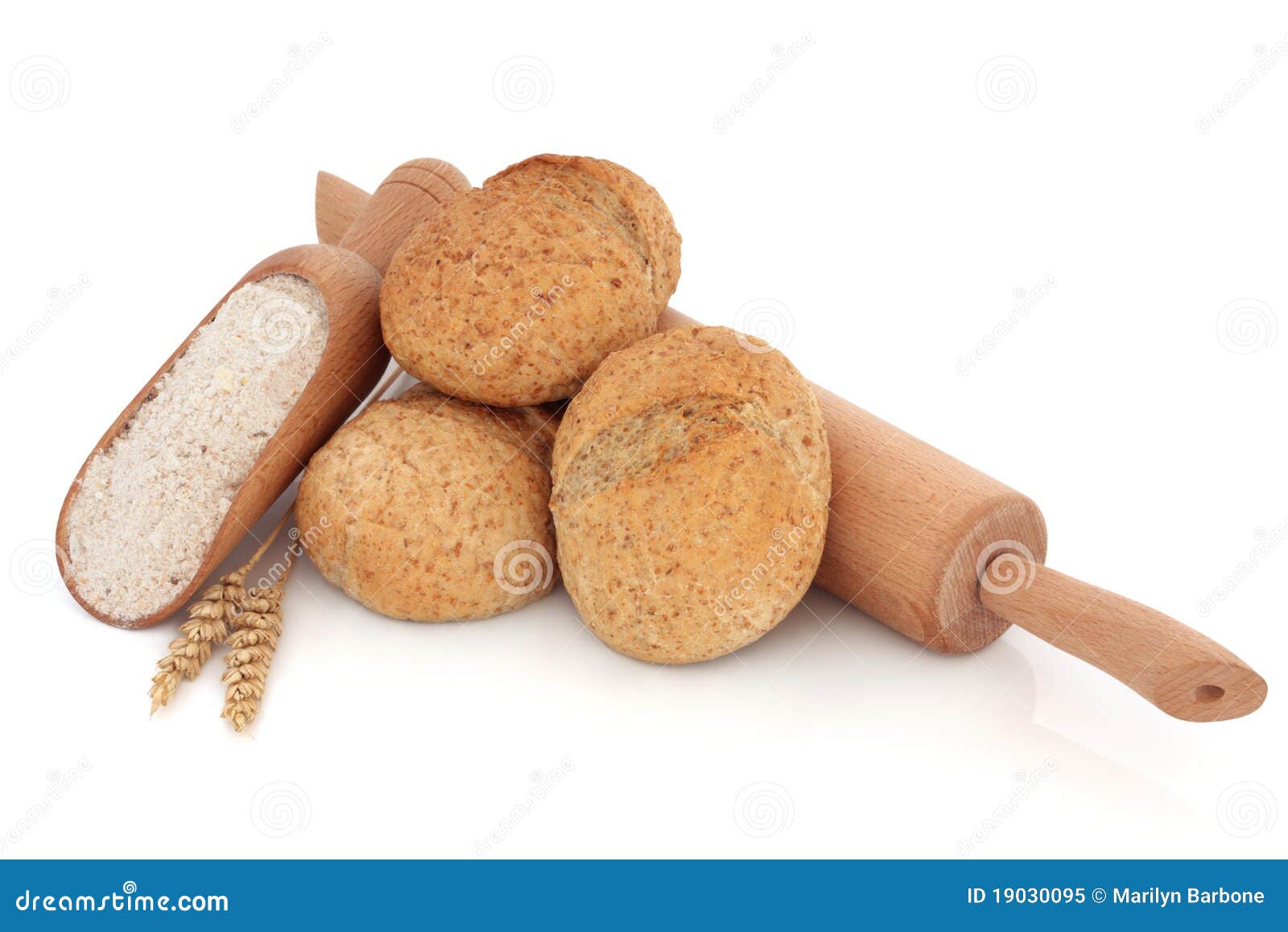 Pane intero Rolls. Pila del rullo di pane con farina intera in una paletta ed in un perno di rotolamento di legno con frumento allentato, sopra priorità bassa bianca.