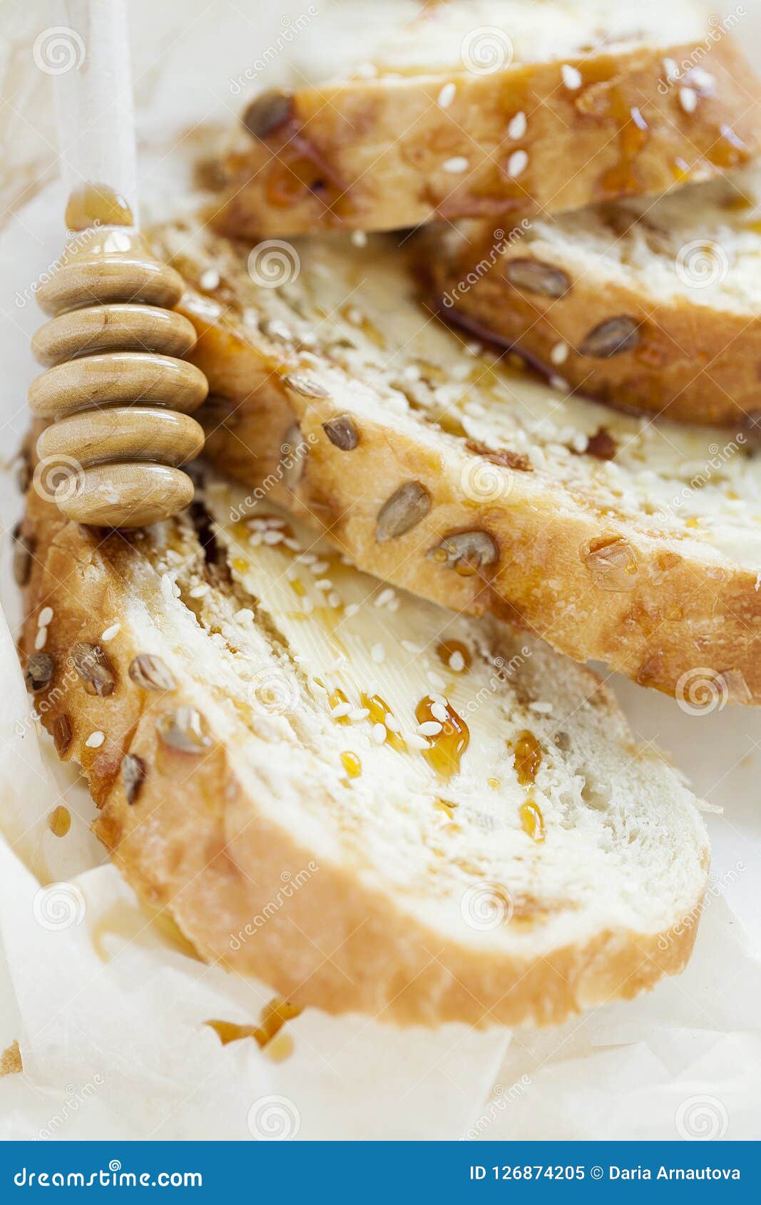 Pane tostato del grano per la prima colazione con burro e miele su fondo bianco closeup. Pane tostato croccante tostato del pane integrale con burro, miele e semi di sesamo su fondo bianco fine sana della prima colazione su verticalmente