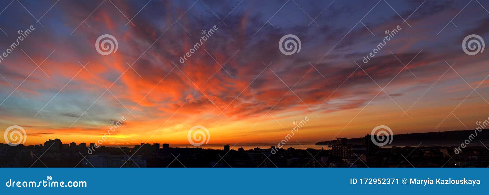 panorama of dawn fire in the sky over a small seaside city. golden red clouds just before the sunrise. scenic landscape at sunrise